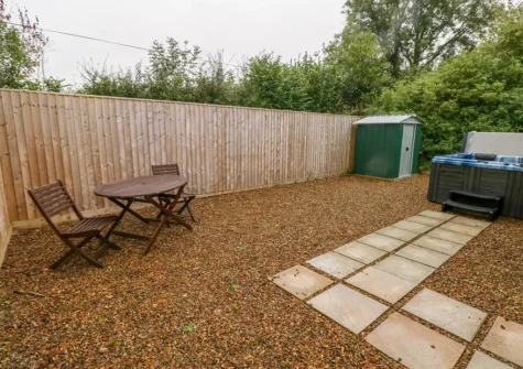 The pebbled patio & hot tub at 1 Hornbeam Lodge, Camp Hill