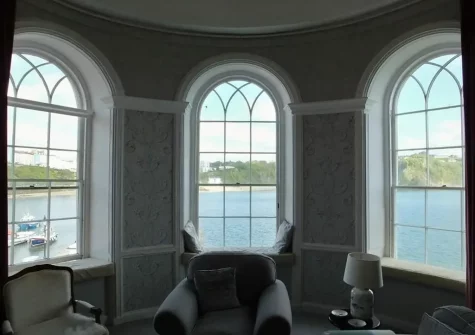 The living room is flooded with natural light through several arched windows