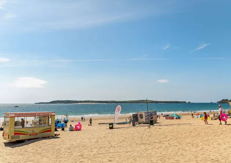Spanning a mile and a half with its golden sands and dune-backed shores, Tenby South Beach offers a serene yet vibrant setting